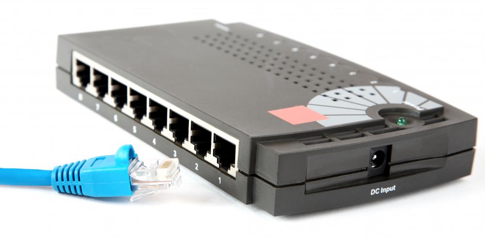 A black 8-port network box with ports numbered 1 to 8 and a DC input jack, next to a blue RJ-45 patch cable